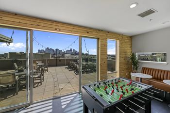 A foosball table is in the middle of a sunny room with sliding glass doors.